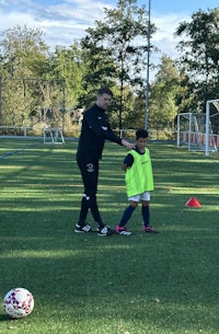 a young boy is standing next to a man on a soccer field